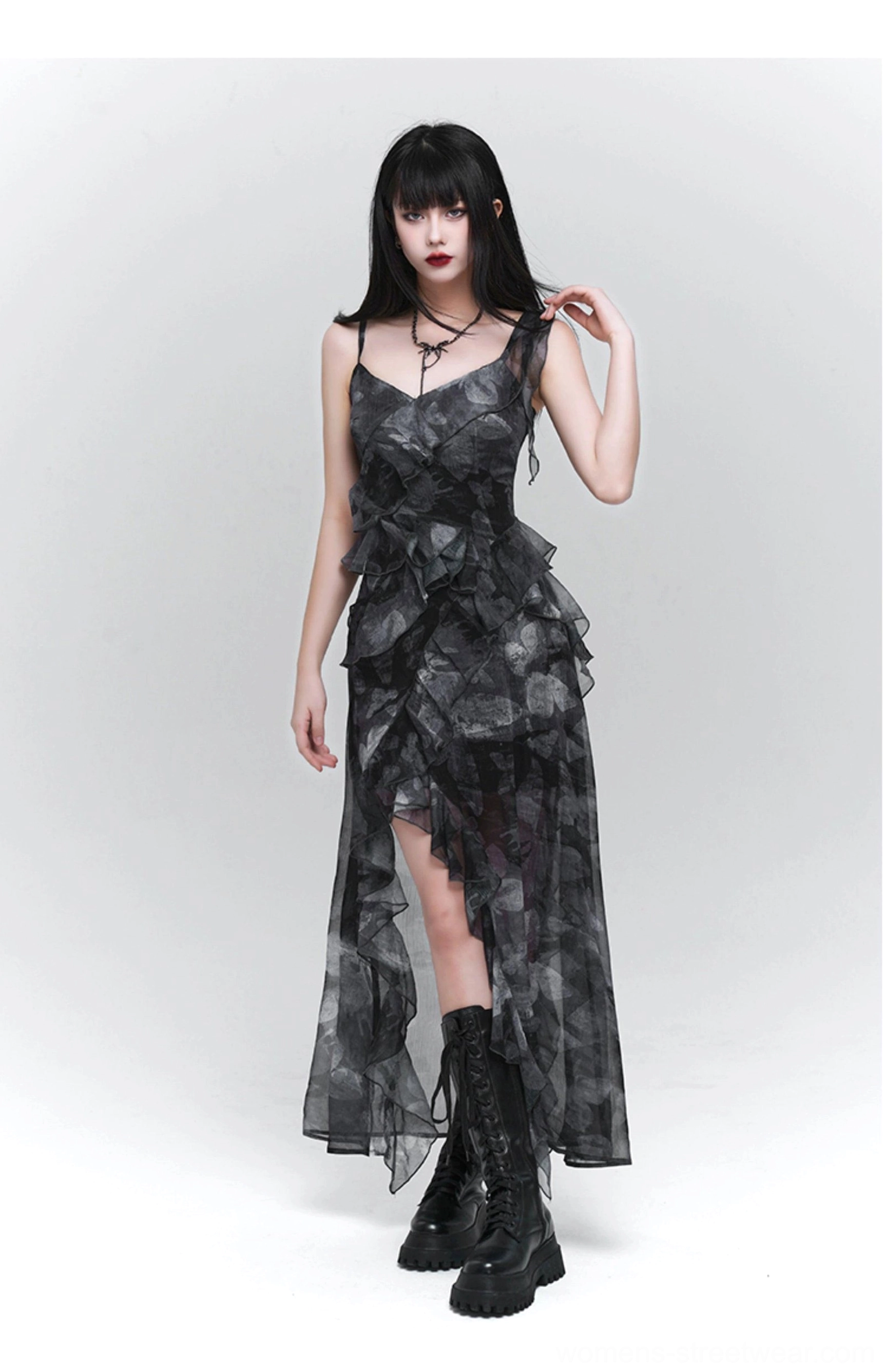 Oblique view of a sheer chiffon dark floral dress with asymmetrical ruffled hem, fitted waist, high side slit, and gothic streetwear styling