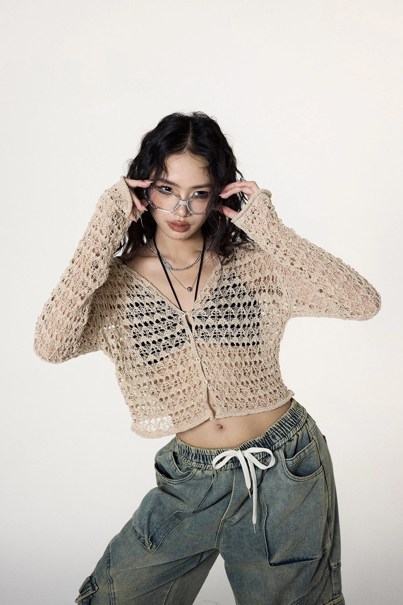 Low-angle front view of a sheer khaki crochet V-neck crop cardigan with button-front styling