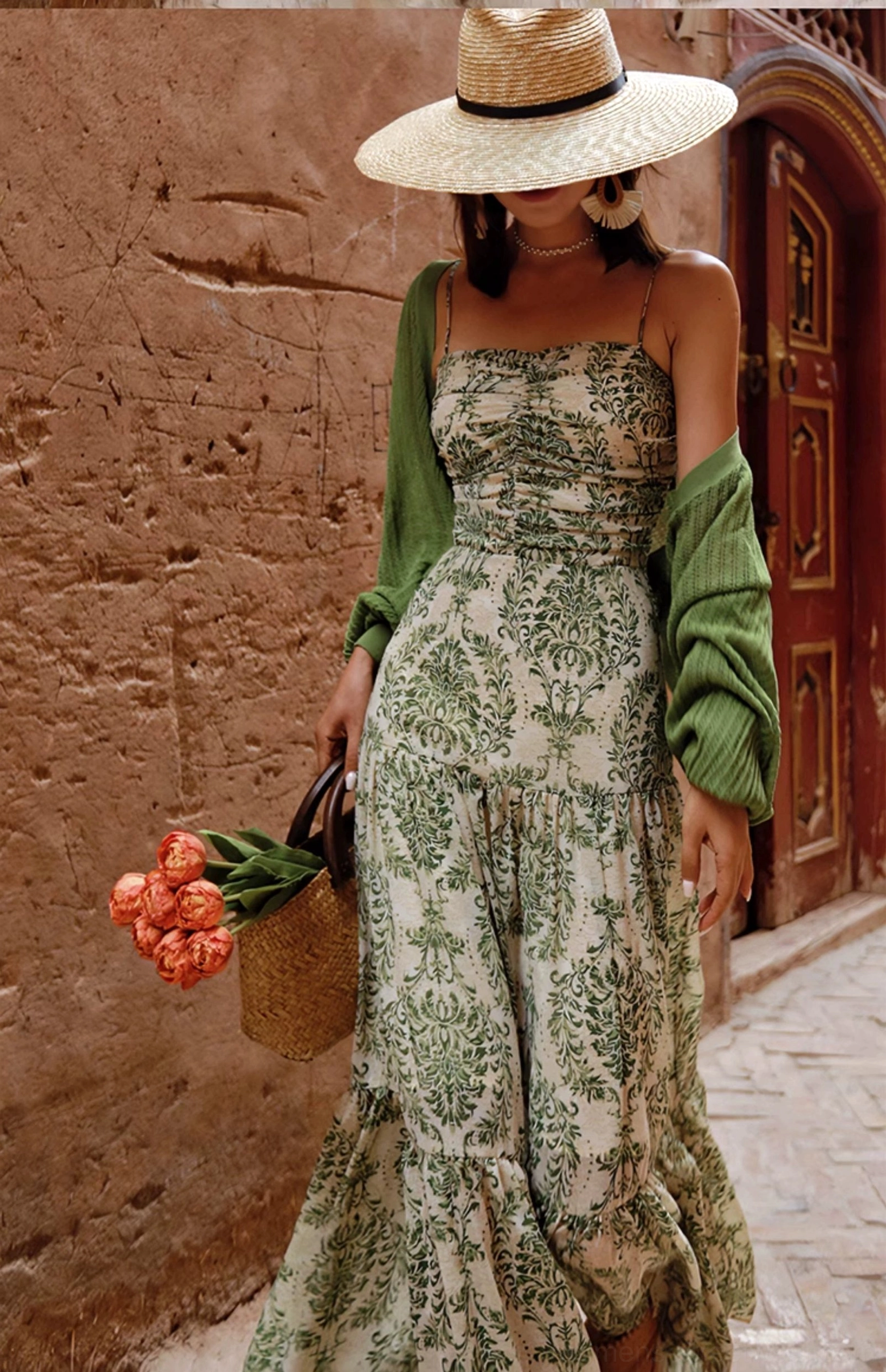 Green open-knit batwing shrug cardigan styled with a tiered floral maxi dress and straw hat