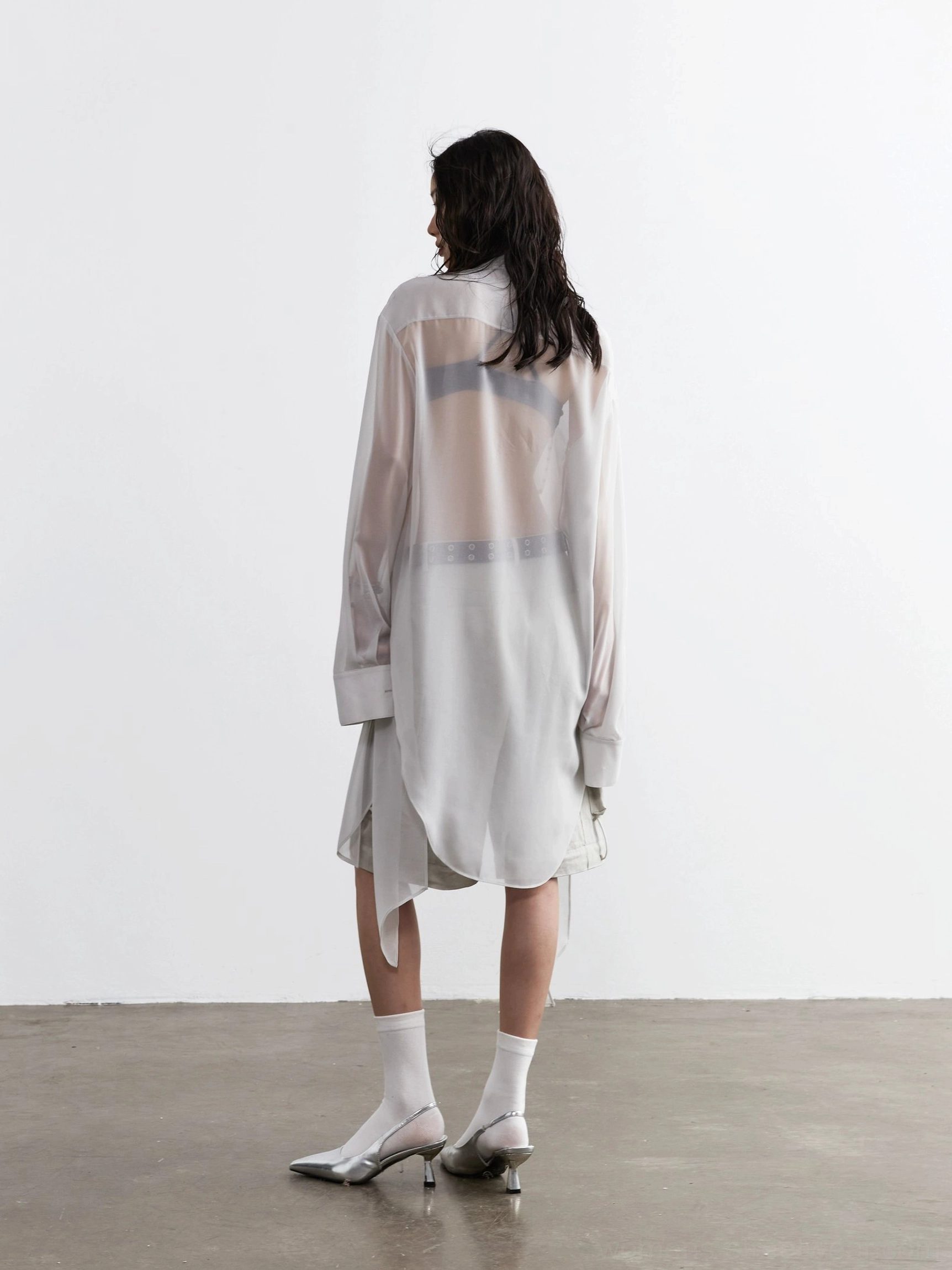 Back view of a sheer long-sleeve neck-tie blouse with blue striped panel and curved high-low hem