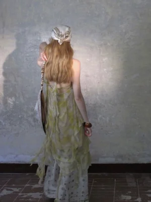 Back view of a sheer tie-dye ruffle maxi dress with an open halter back and layered flowy skirt