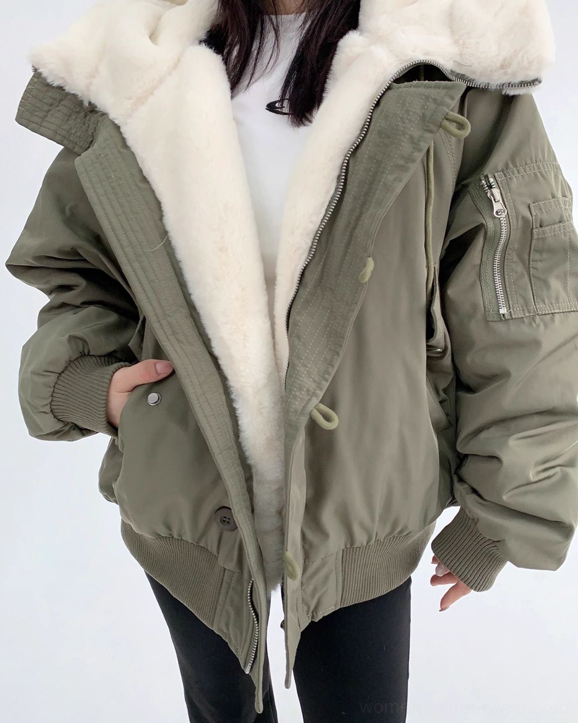 Close-up of oversized sherpa-lined bomber jacket showing plush off-white interior, zippered sleeve pocket, and waist drawstring