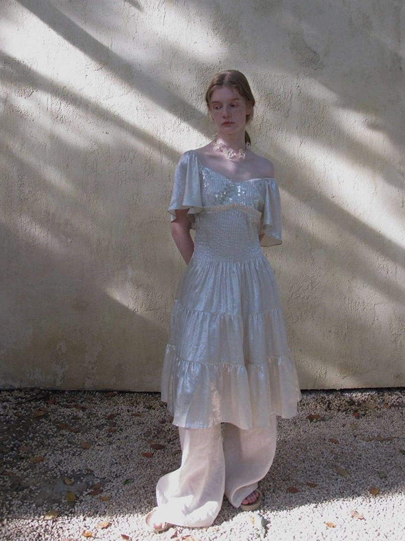 Light blue shimmer off shoulder tiered midi dress with square neckline ruffled sleeves and white wide leg pants