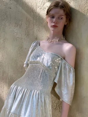 Champagne shimmer off shoulder tiered midi dress with ruffled sleeve and sequined texture photographed outdoors
