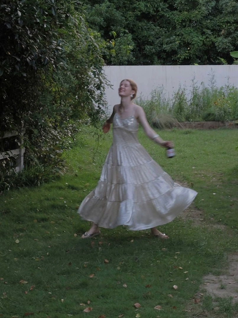 Light champagne spaghetti strap shimmer tiered dress moving outdoors with airy layered skirt