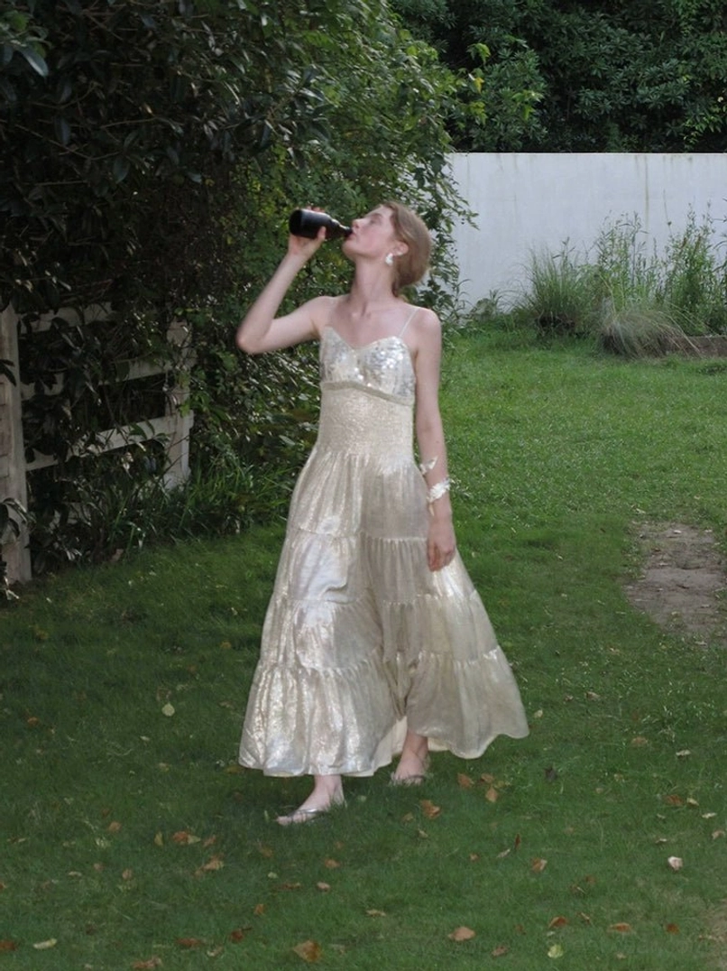 Champagne gold strapless sweetheart shimmer tiered maxi dress with luminous flowing skirt in garden setting