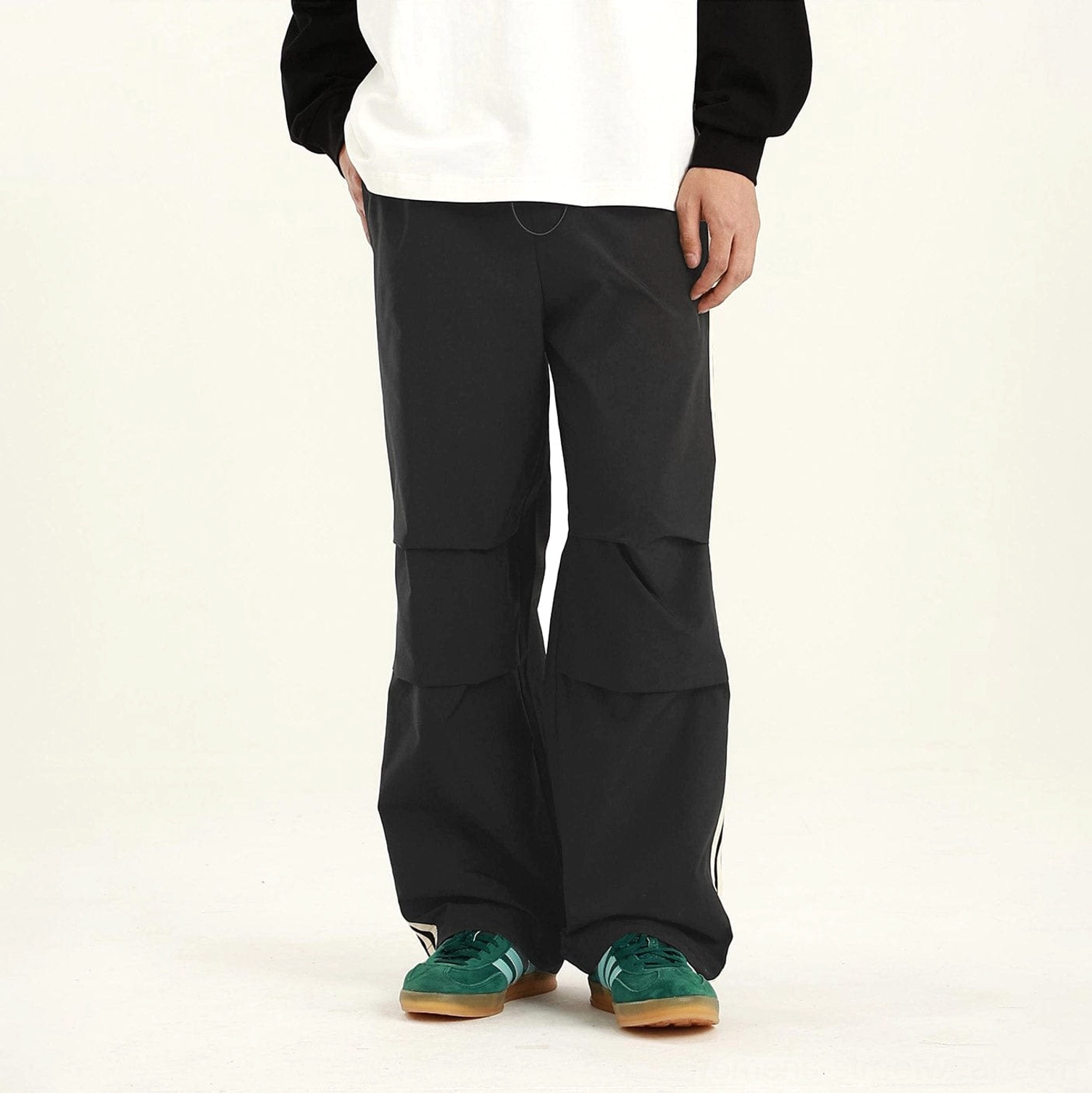 Black streetwear cargo pants with relaxed straight-leg silhouette and dimensional articulated knee pleats