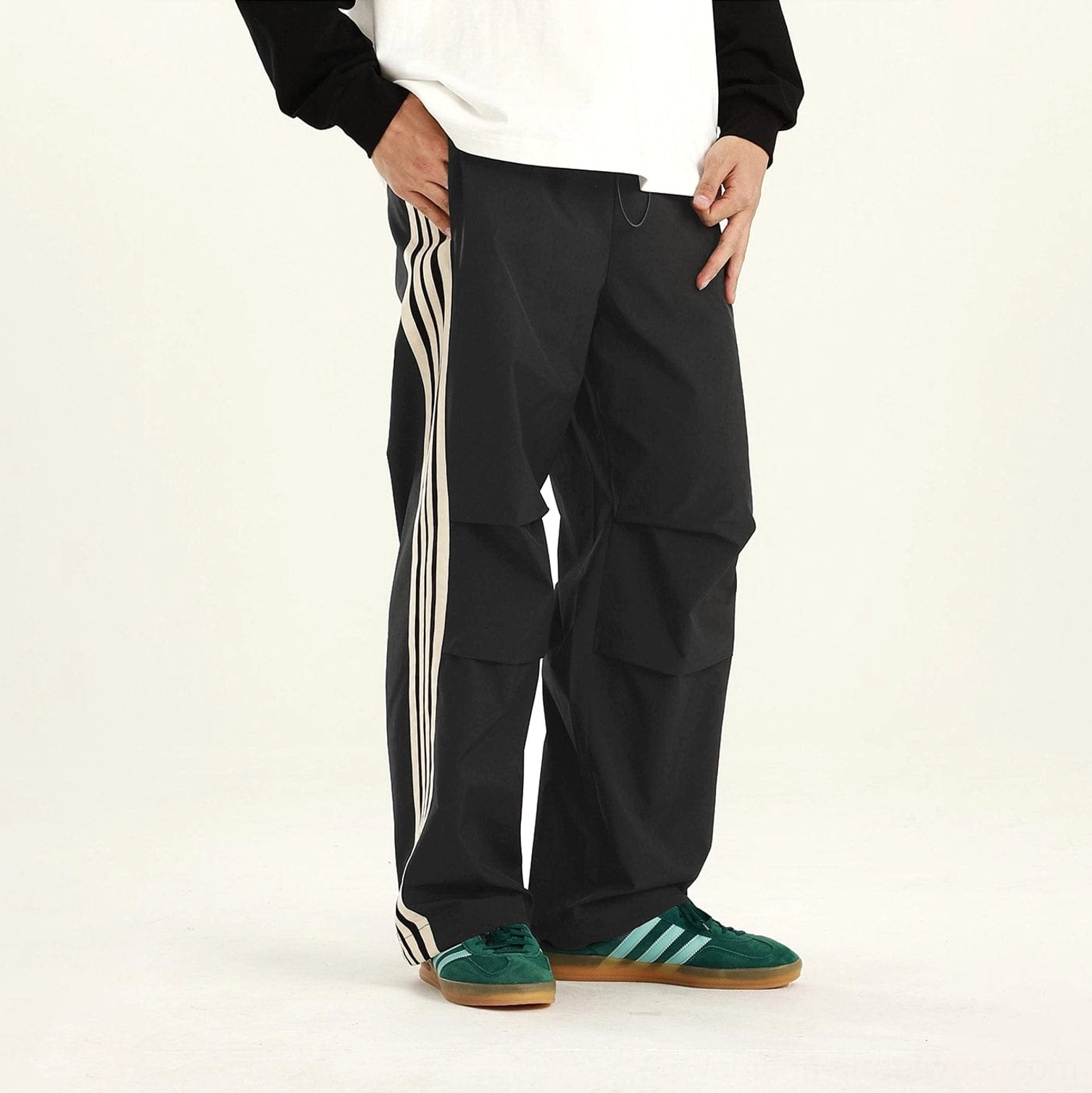 Black side-stripe streetwear cargo pants with white three-stripe detail and relaxed articulated knee design