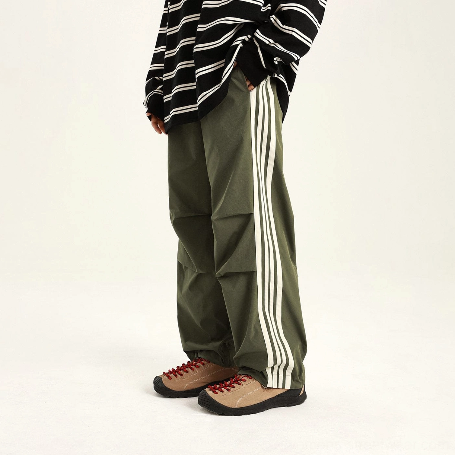 Green side-stripe streetwear cargo pants with white athletic stripes, relaxed fit, and pleated knees