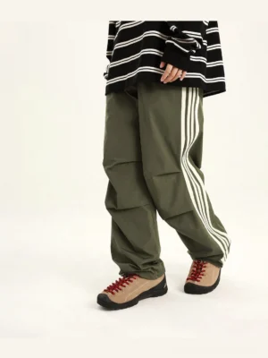Green side-stripe streetwear cargo pants with relaxed straight-leg fit, white three-stripe detail, and articulated knee pleats