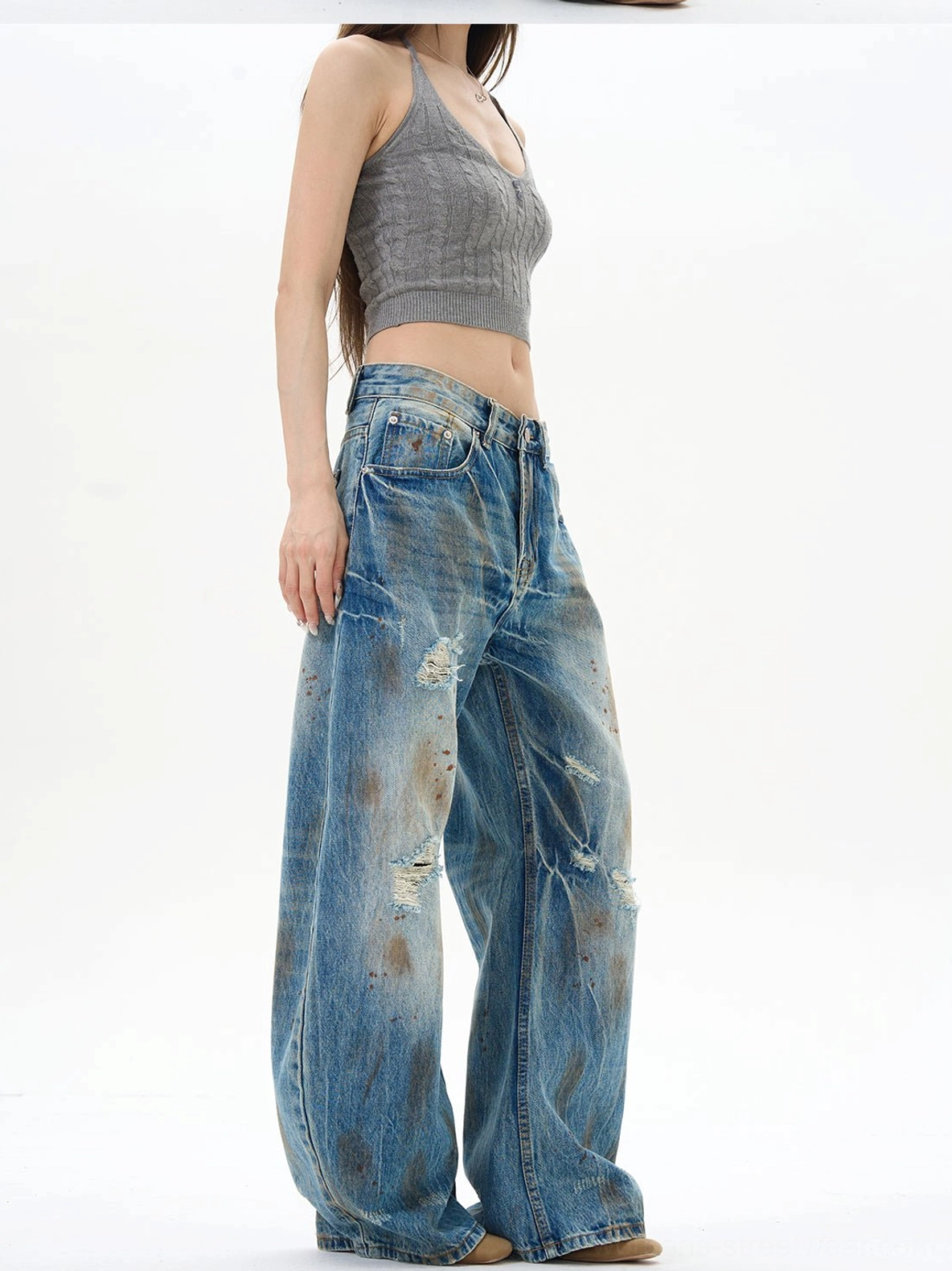 Side view of relaxed women's wide-leg distressed jeans with dramatic drape, faded blue denim, and vintage grunge streetwear styling