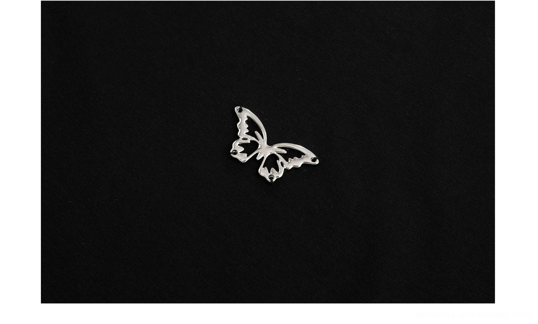 Close-up detail of the silver 3D butterfly emblem placed on the chest of a fitted maxi dress
