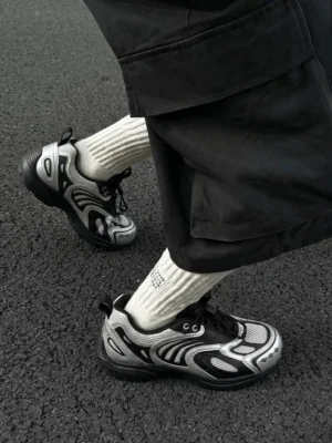 Silver black futuristic mesh runner sneakers worn with ribbed socks and black cargo shorts on asphalt streetwear outfit