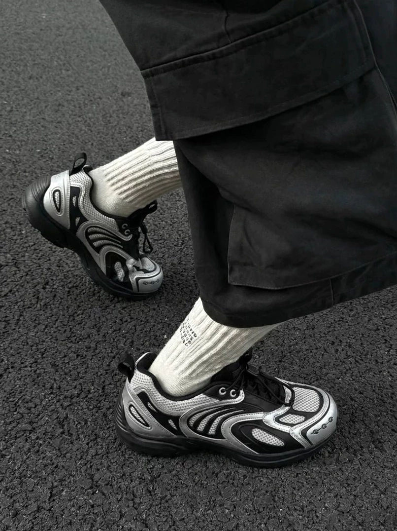 Silver black futuristic mesh runner sneakers worn with ribbed socks and black cargo shorts on asphalt streetwear outfit