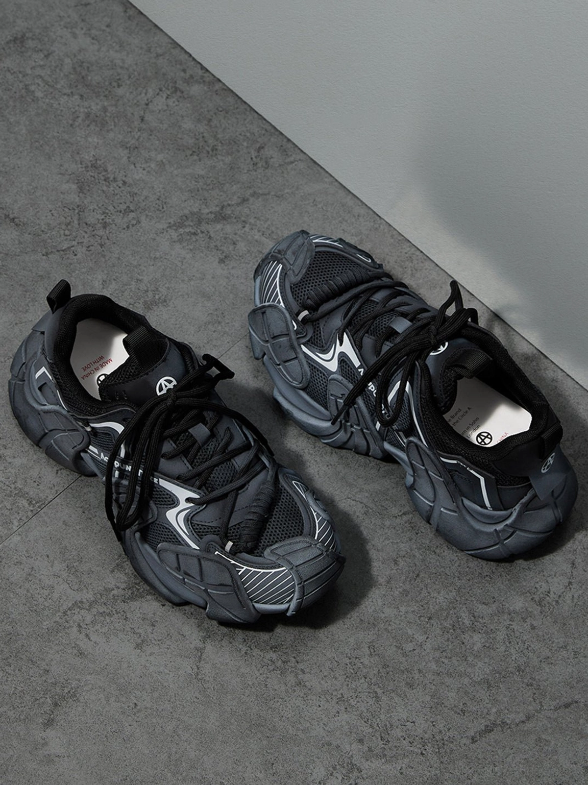 Dark grey silver chunky platform sneakers flat lay on concrete with textured mesh upper