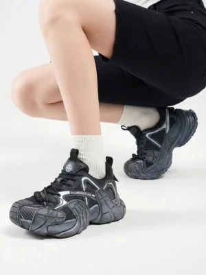 Silver cage panel chunky platform sneakers worn with white crew socks and black shorts in studio