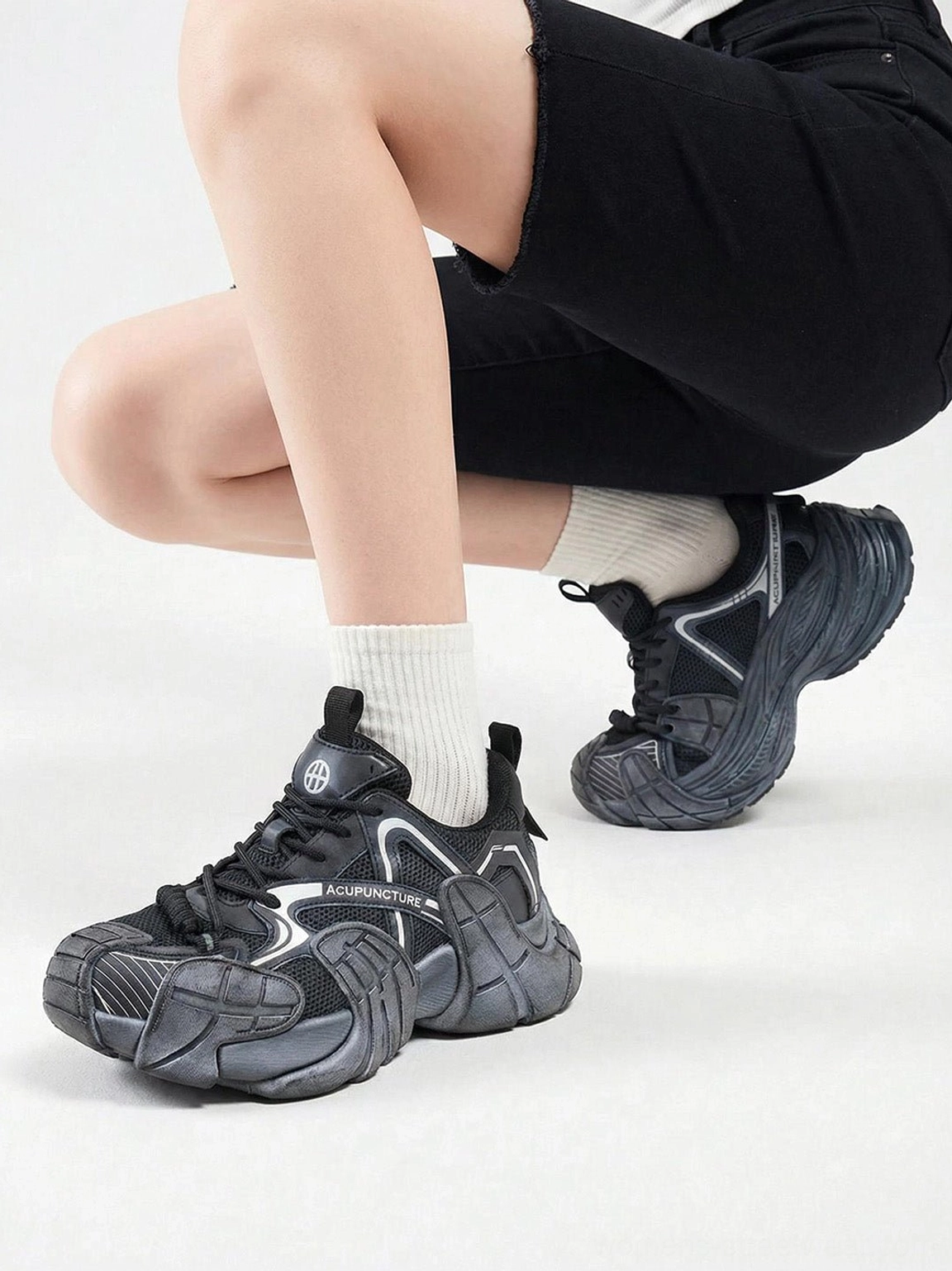 Silver cage panel chunky platform sneakers worn with white crew socks and black shorts in studio