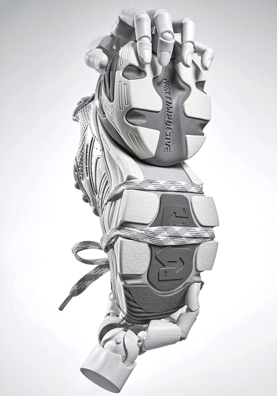 Bottom view of silver chunky streetwear sneakers held by robotic hands with a thick textured anti slip outsole