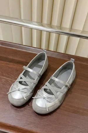 Silver cross strap Mary Jane ballet flats with round toe bow displayed in a top down flat lay on a dark wood table