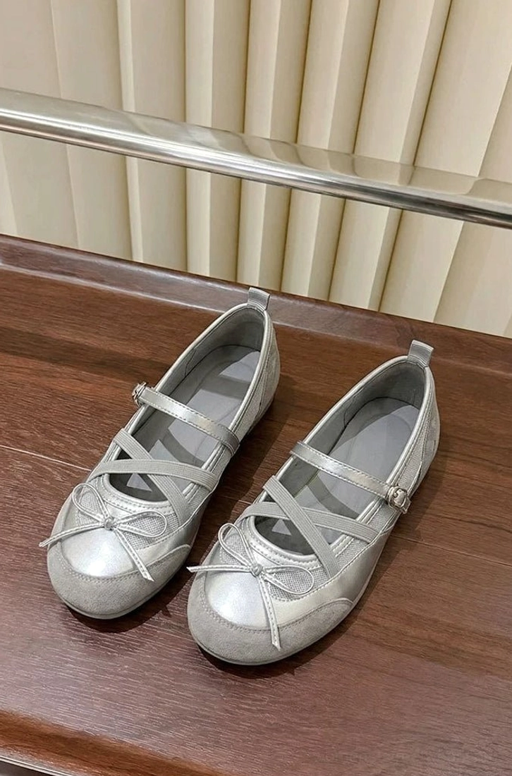 Silver cross strap Mary Jane ballet flats with round toe bow displayed in a top down flat lay on a dark wood table