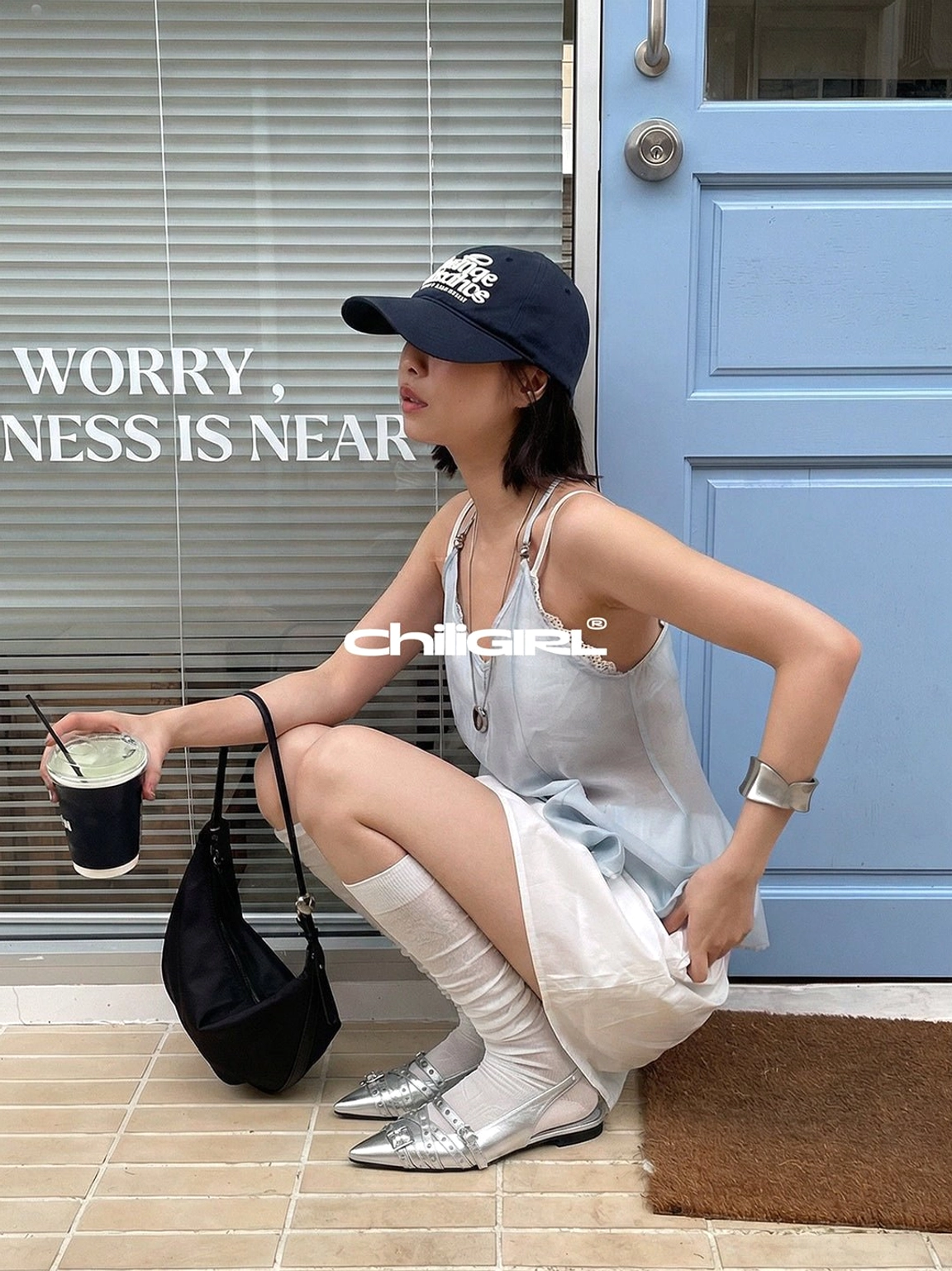 Silver double-buckle slingback flats styled with sheer socks, a white mini skirt, and a casual summer streetwear look