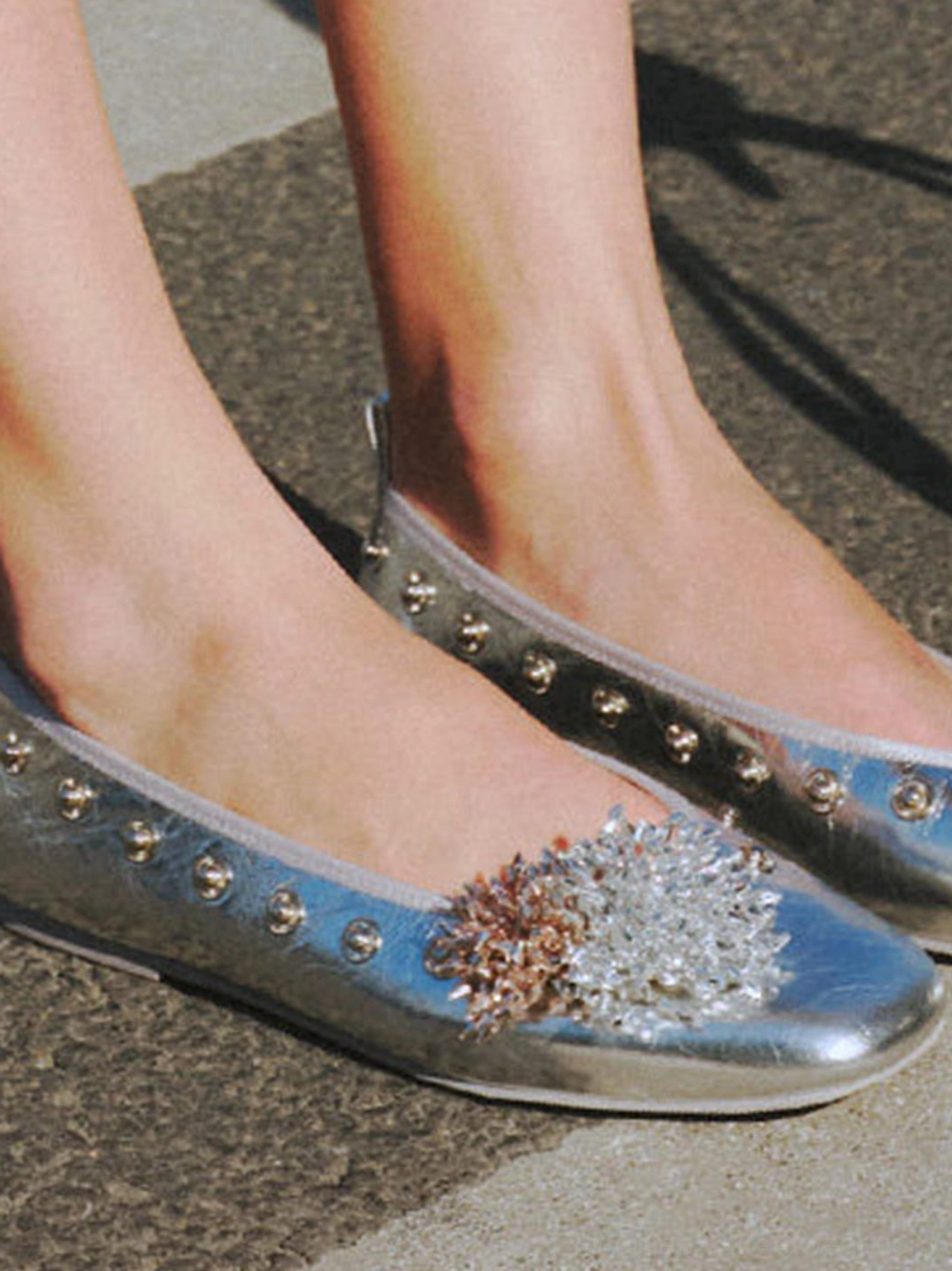Silver floral embellished square-toe flats worn outdoors with studded trim and crystal flower detail