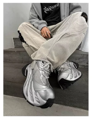 Silver futuristic platform runner sneakers worn with ripped grey jeans and oversized hoodie in a modern urban streetwear outfit
