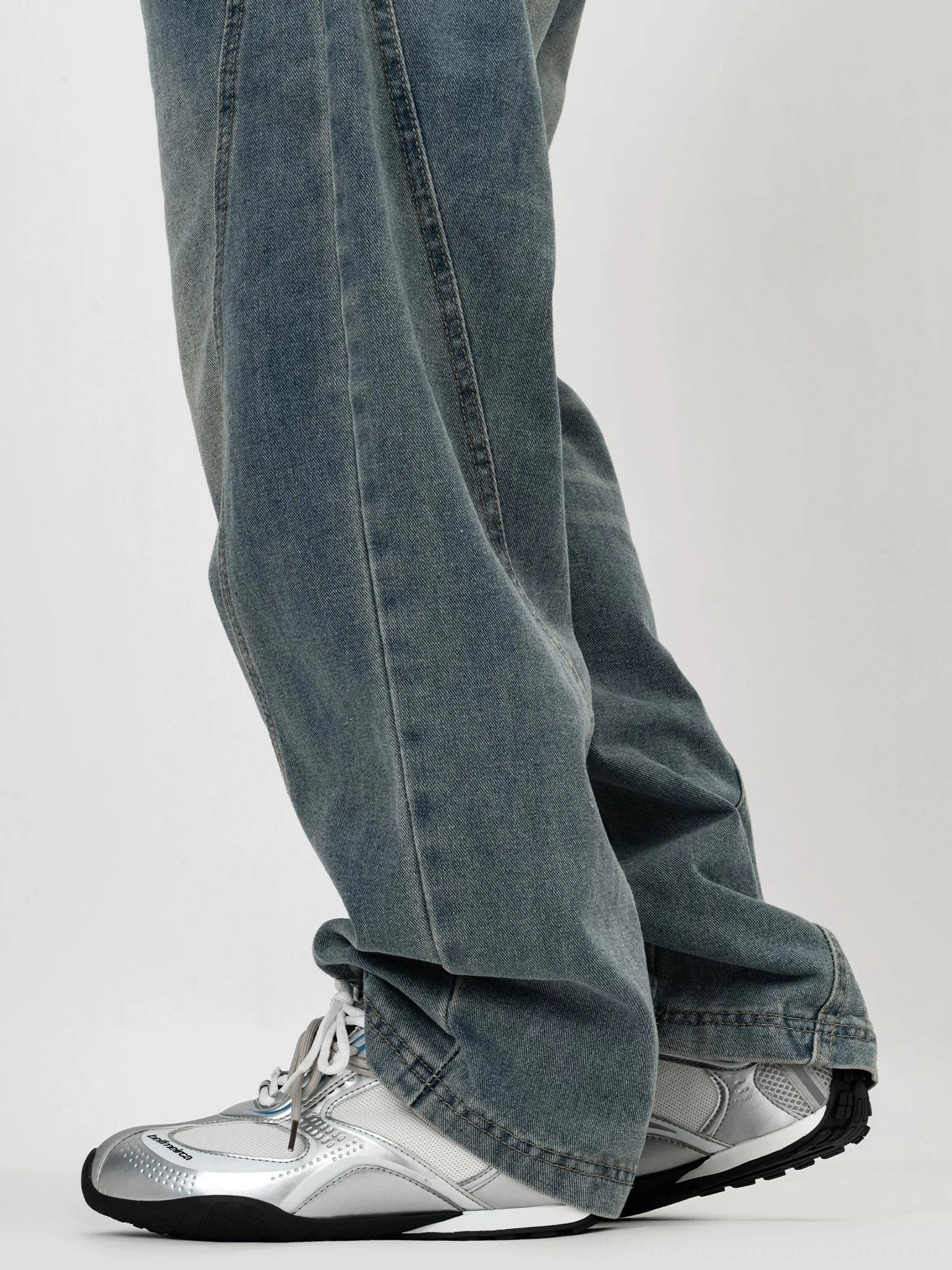 Silver-gray retro low-top sneakers worn with washed blue straight-leg jeans, streamlined silhouette, metallic accents, and comfortable lace-up fit