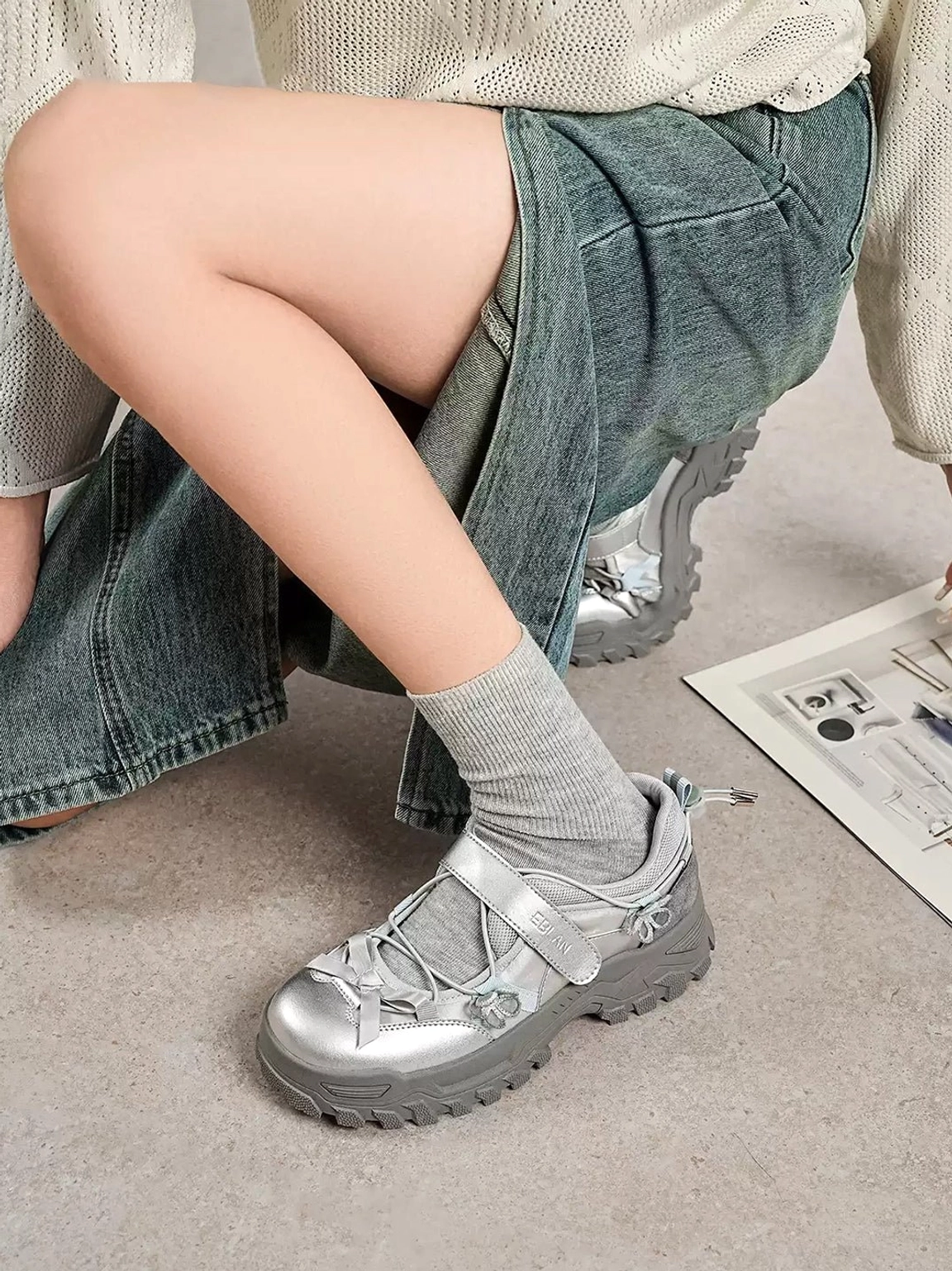 Silver gray Mary Jane platform sneakers worn with denim pants knitwear and crew socks in a relaxed urban outfit