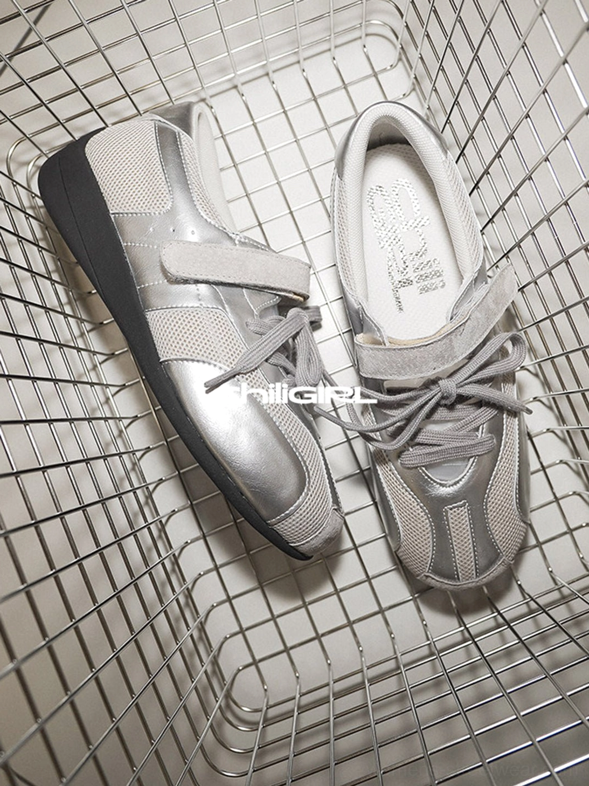 Silver and gray mesh Velcro strap sneakers arranged in a wire basket, highlighting the retro trainer shape and metallic upper