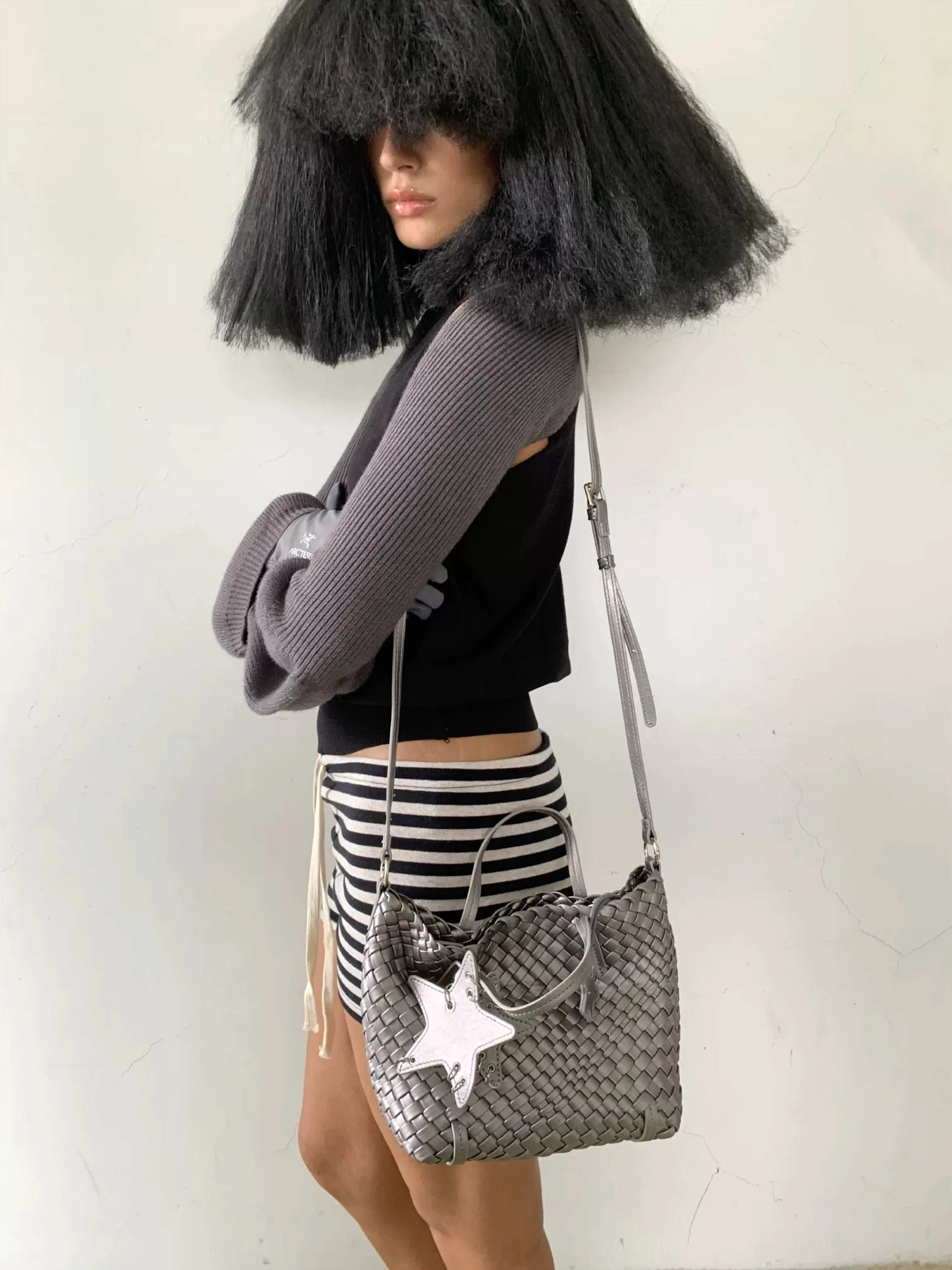 Silver gray mini woven star charm shoulder bag worn at the side with detachable crossbody strap