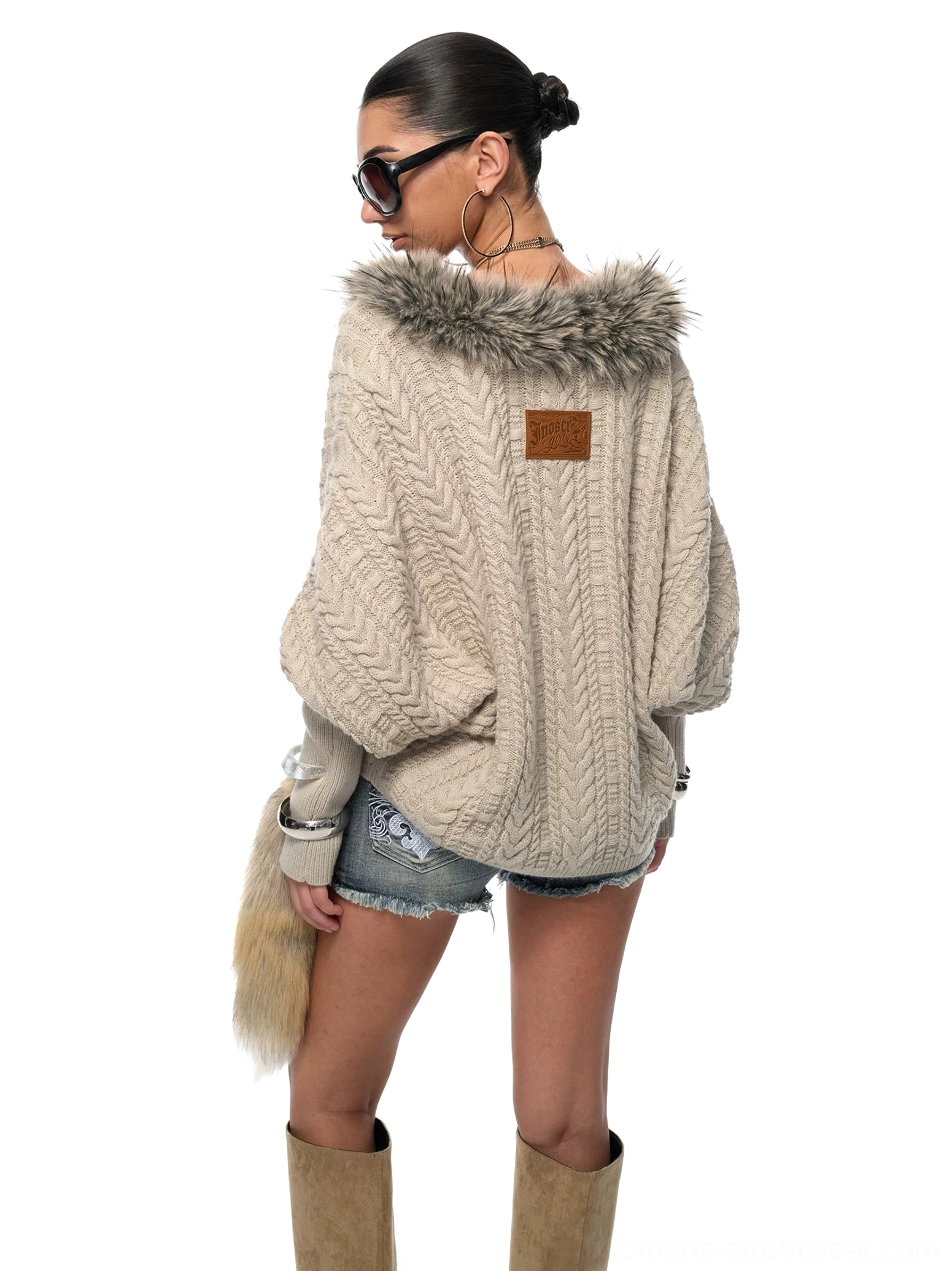 Back view of a silver gray slouchy cable knit sweater showing the leather-look patch and faux fur tail detail