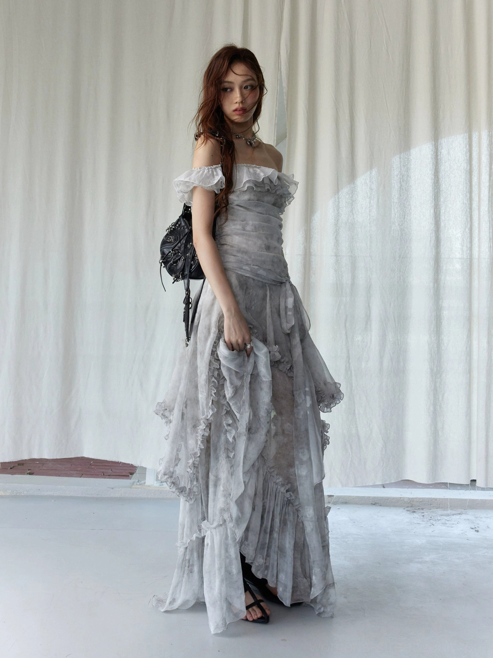 Three-quarter view of silver gray tie-dye maxi dress with off-shoulder ruffled trim, tiered skirt, and sheer flowing fabric