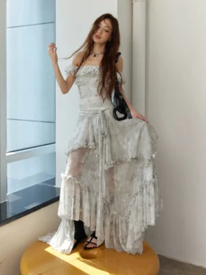 Silver gray tie-dye off-shoulder maxi dress with asymmetrical ruffled hem styled with black sandals and a black handbag