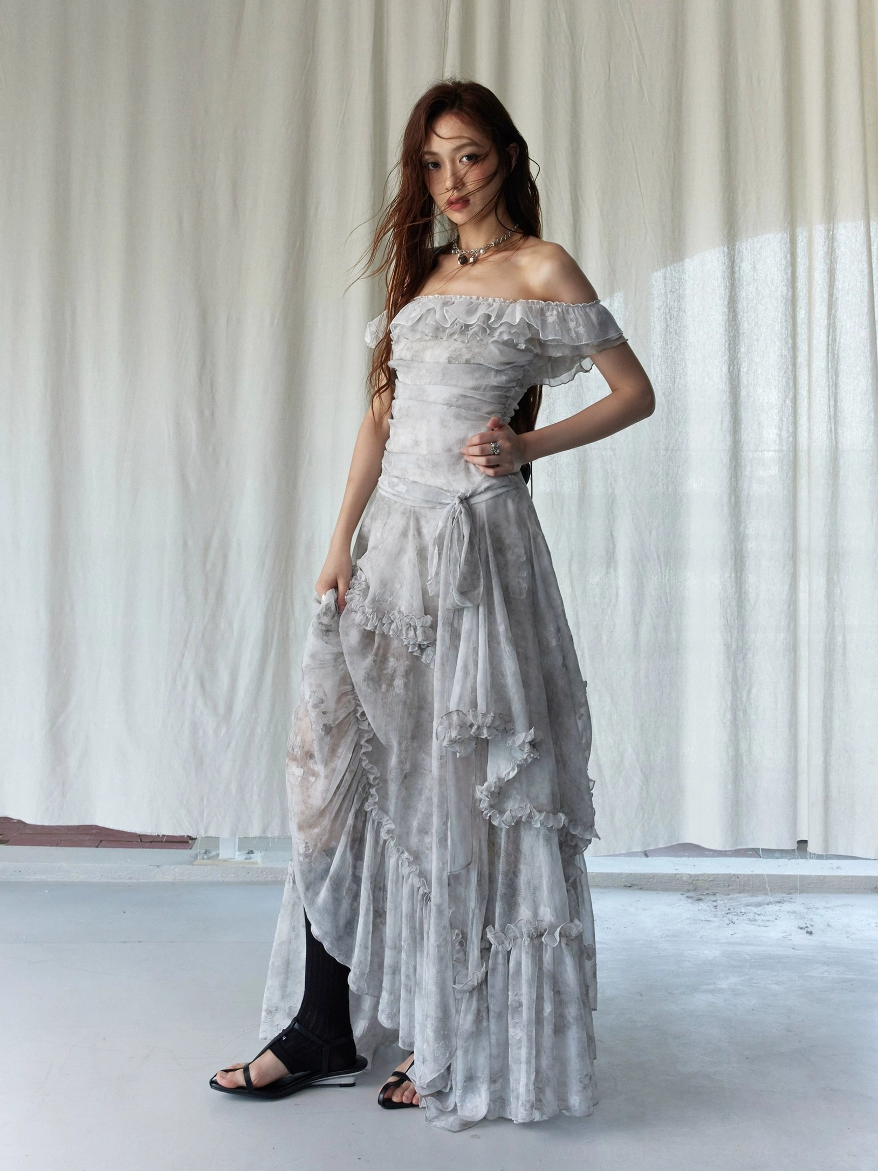 Side view of silver gray tie-dye off-shoulder ruffled maxi dress with flowing floor-length sheer fabric and ruched bodice
