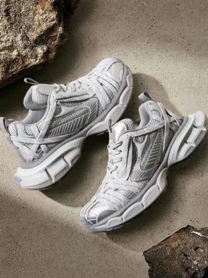 Silver layered mesh chunky runner sneakers displayed from above on a cement-style surface with breathable mesh panels and metallic sole accents