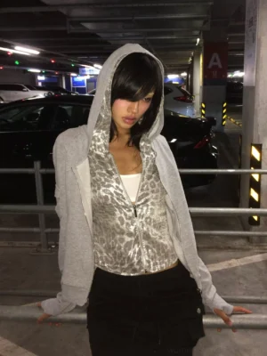 Heather gray cropped slim zip hoodie with silver leopard layered hood styled with black wide-leg pants in a parking garage