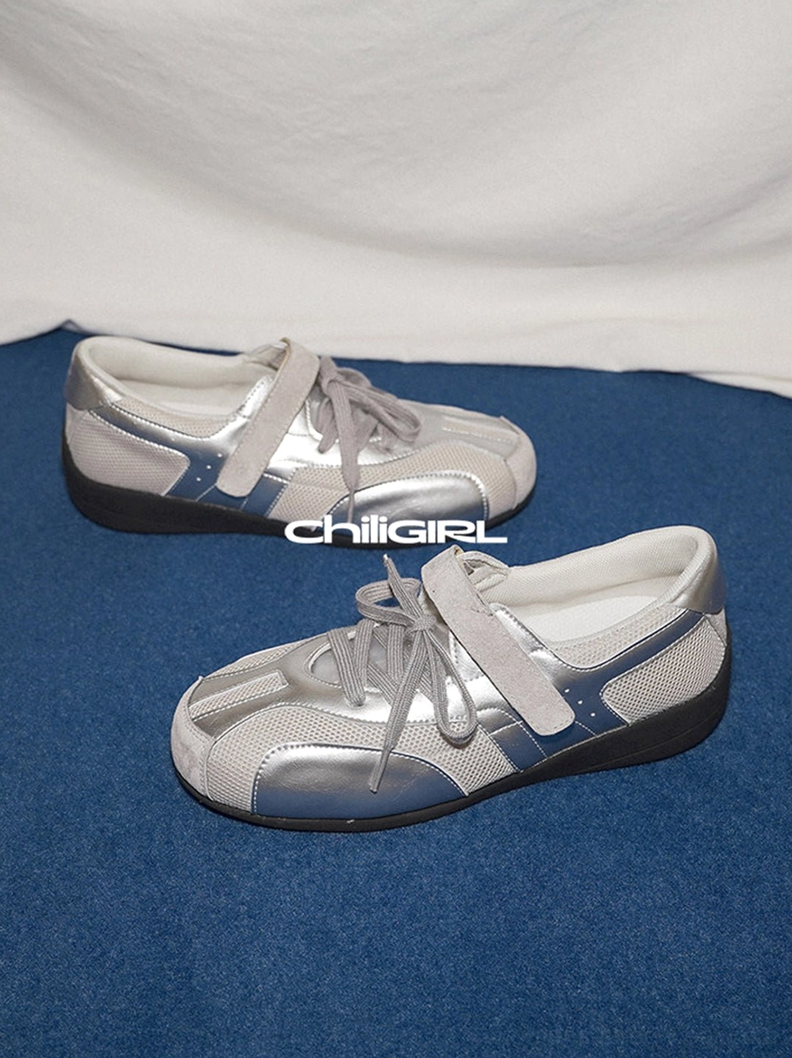 Silver mesh streetwear sneakers displayed from an angled side view with gray-blue side detailing and layered Velcro strap design