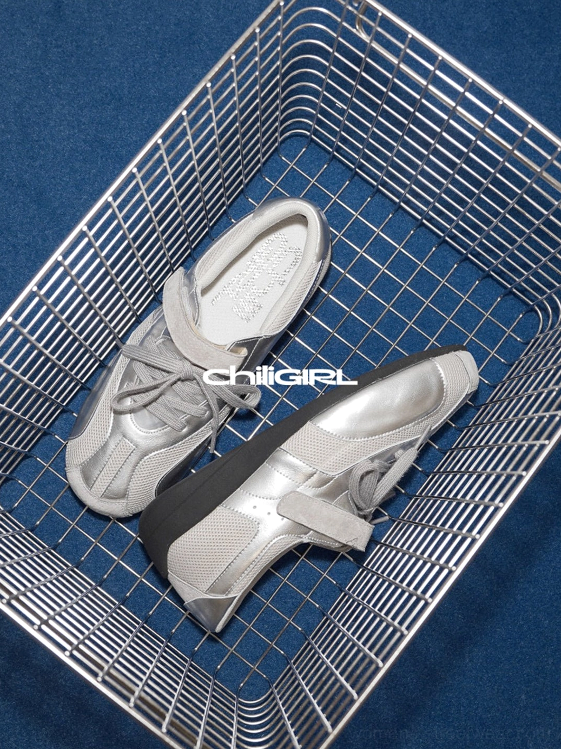 Silver mesh Velcro sneakers in a wire basket with black rubber outsole visible from an angled top view