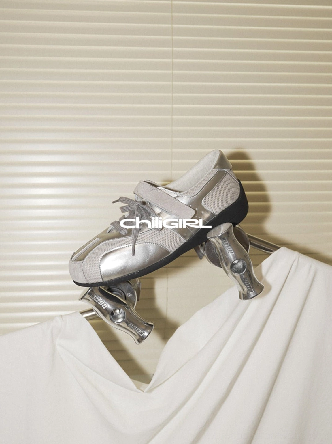 Silver mesh Velcro strap sneakers presented in a detailed product view, showing the metallic upper and low-top trainer construction