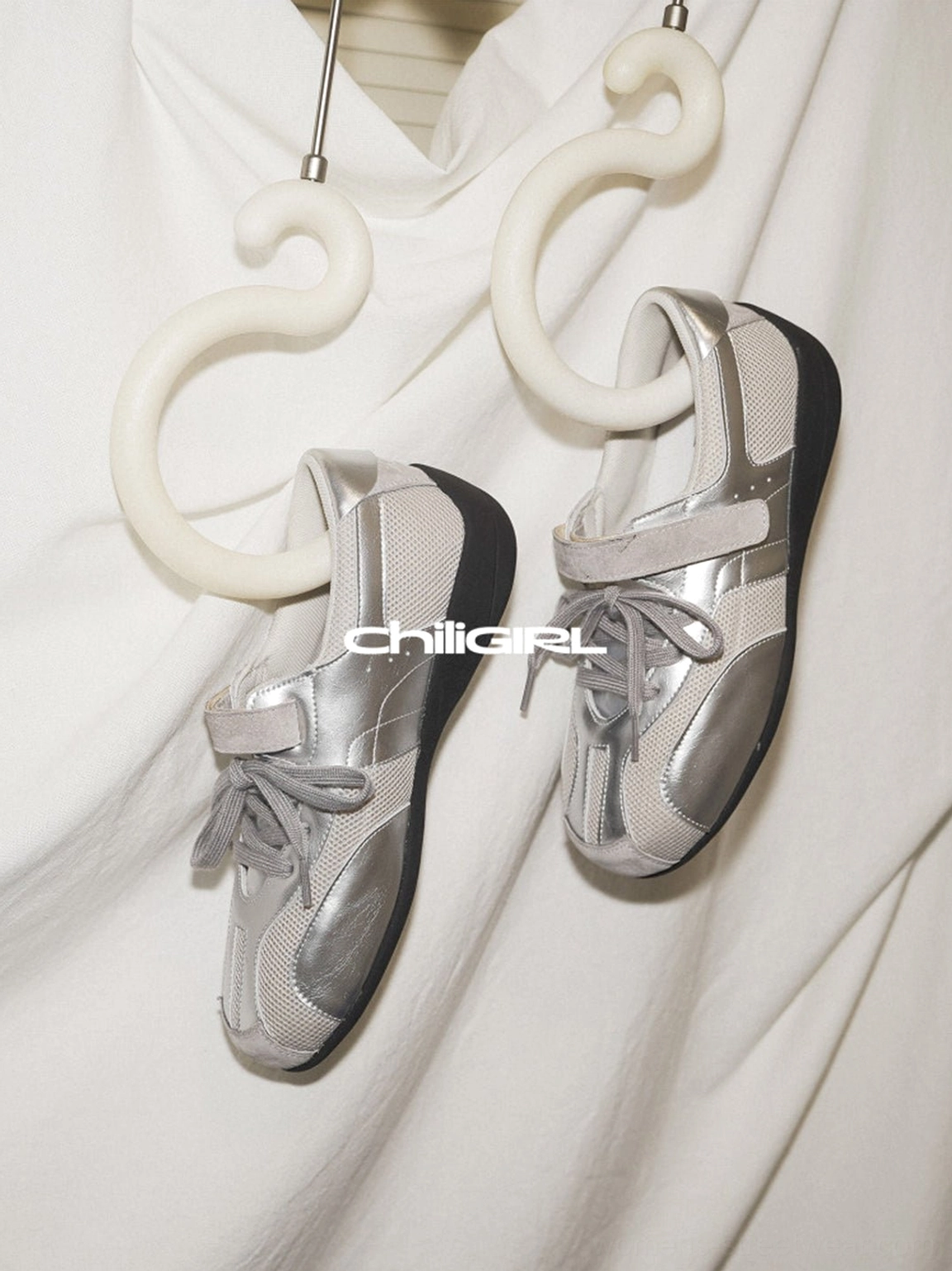 Side profile of silver mesh Velcro strap trainer sneakers displayed against a light backdrop with futuristic streetwear styling