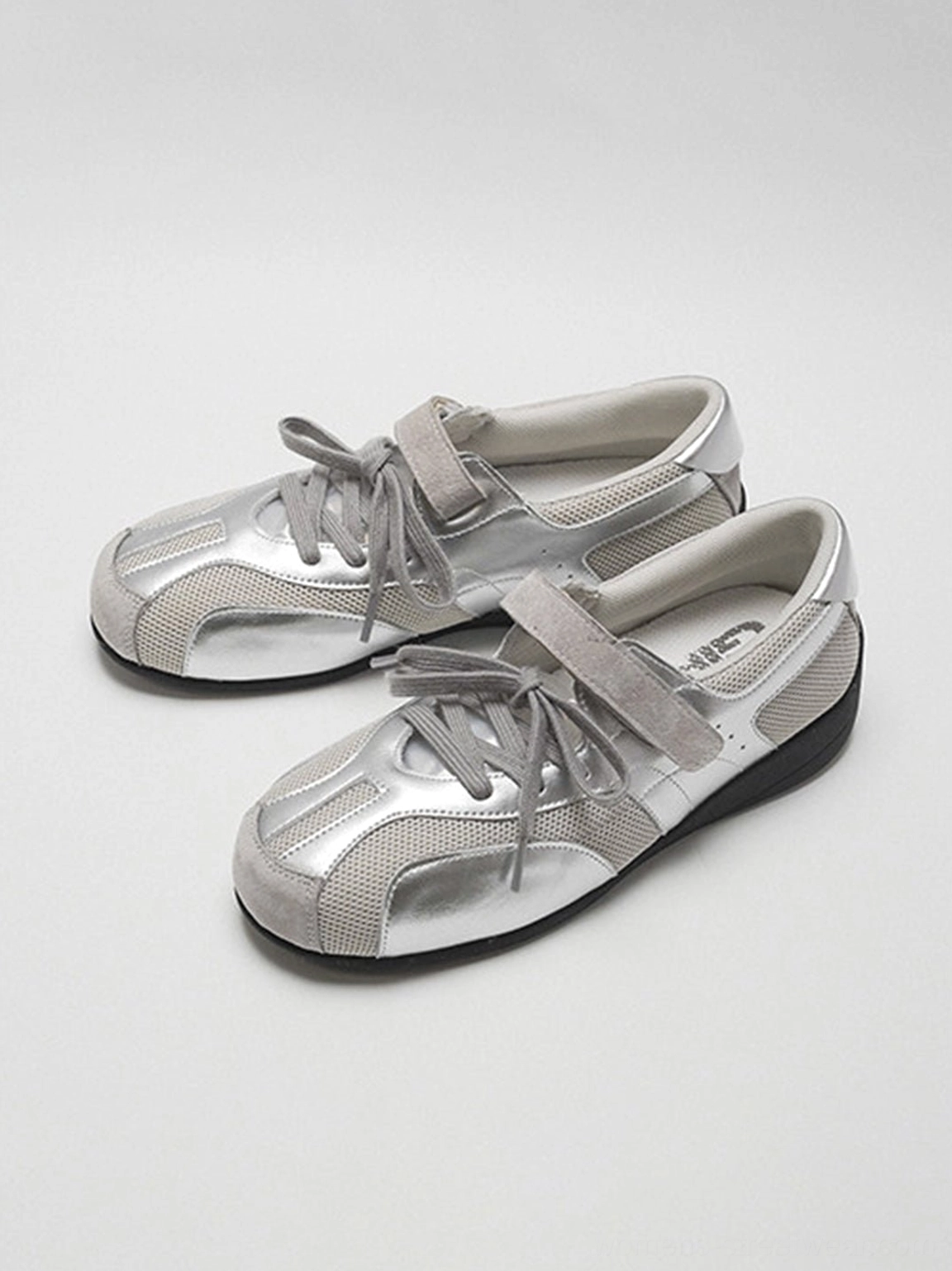 Silver metallic mesh Velcro sneakers shown in three-quarter view with lace-up closure, adjustable strap, and contrasting black outsole