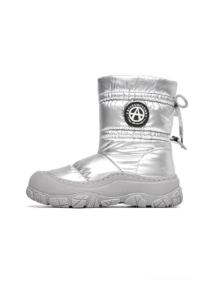 Silver metallic women's puffer snow boot shown in a full left-side studio view with quilted padding, drawstring collar, circular shaft badge, and chunky grey treaded sole