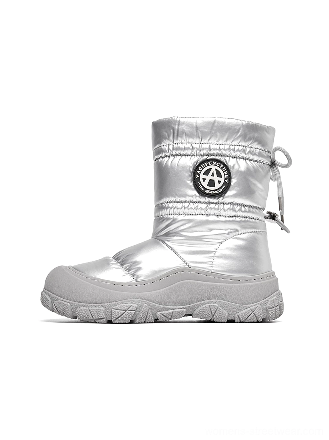 Silver metallic women's puffer snow boot shown in a full left-side studio view with quilted padding, drawstring collar, circular shaft badge, and chunky grey treaded sole