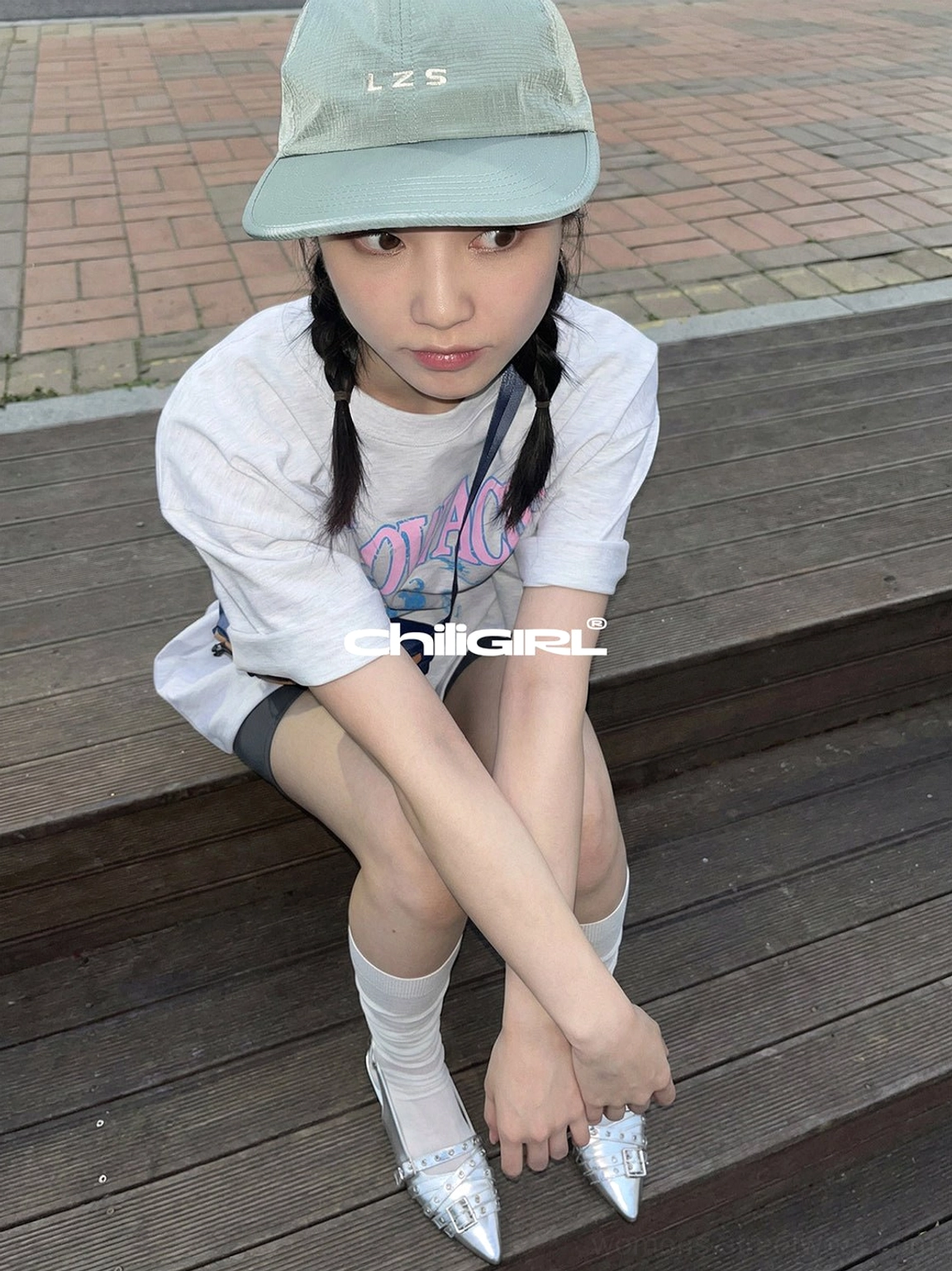 Close-up of silver pointed-toe buckle flats worn with sheer white socks and a casual white tee streetwear outfit