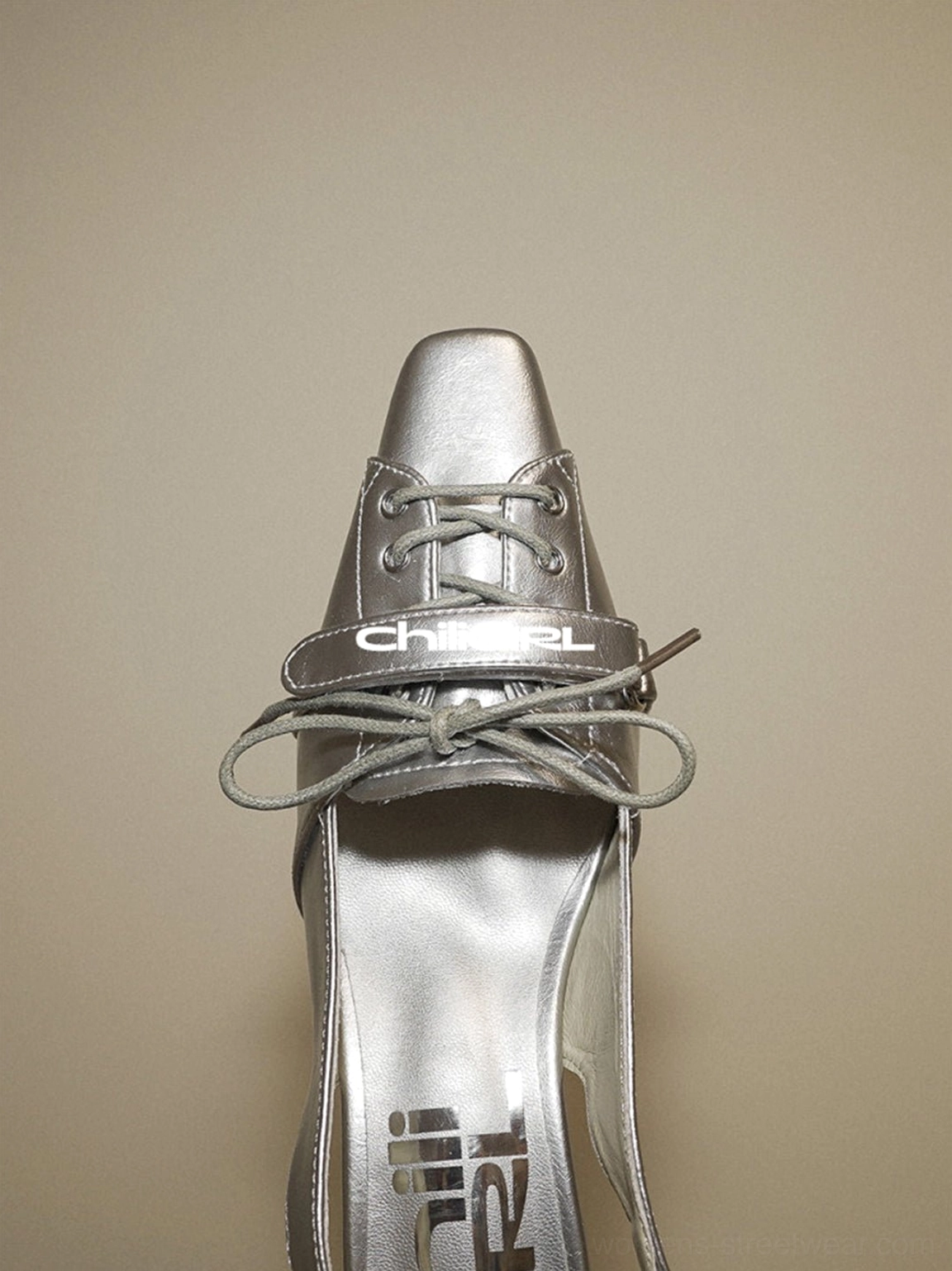 Front close-up of silver pointed-toe slingback kitten heel shoe with bow vamp detail and shiny metallic finish