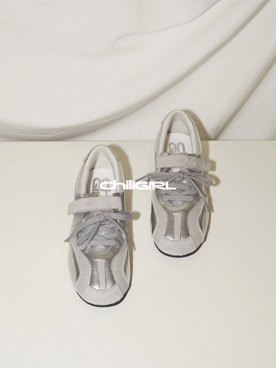 Pair of silver retro-inspired mesh trainer sneakers viewed from above with metallic finish and Y2K streetwear styling