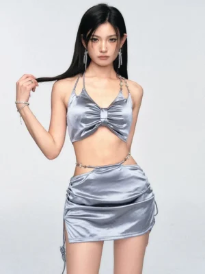 Silver satin bow halter two-piece set with ruched mini skirt and chain waist detail front close-up