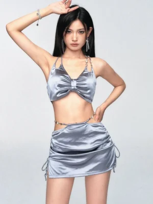 Silver satin bow party outfit with cutout waist halter crop top and adjustable ruched mini skirt