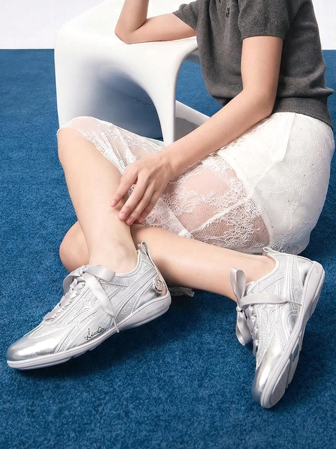 Women's silver sculpted-panel athletic trainers styled with a sheer white lace skirt and modern Korean-inspired streetwear outfit